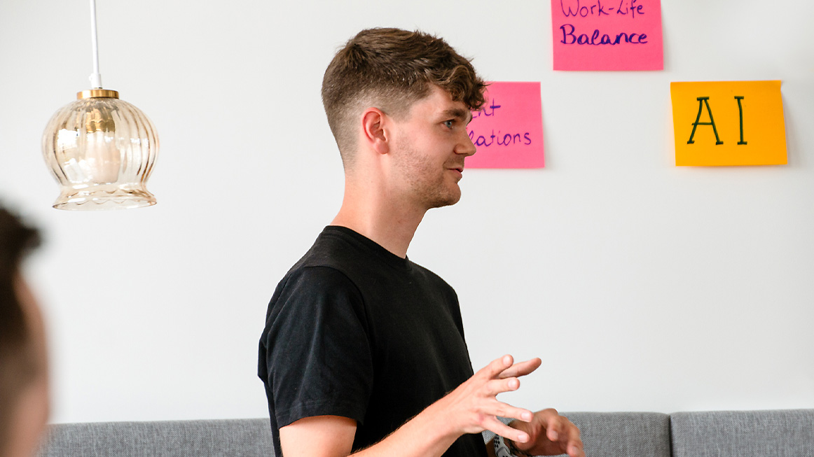 person in white t-shirt infront of a wall with sticky notes in a strategy meeting (Photo)