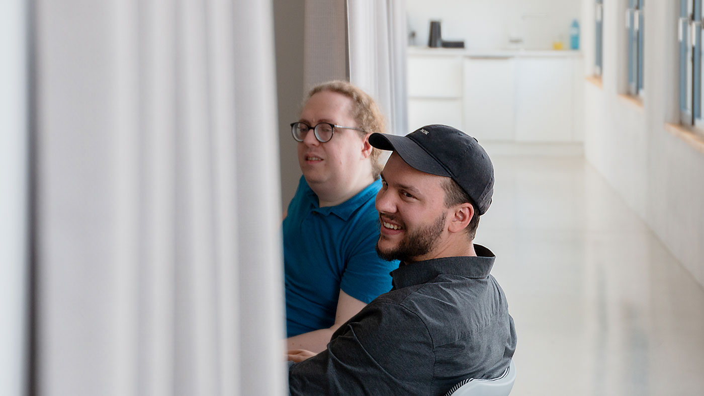 two people, one with glasses one with a cap, discussing table implementation (Photo)